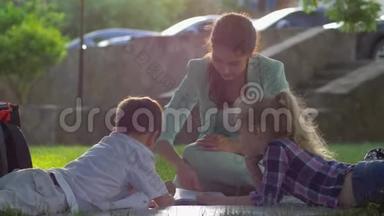 快乐的童年，微笑的妈妈在阳光下为坐在绿色草地上的<strong>小</strong>男孩和<strong>小</strong>女孩<strong>读书</strong>